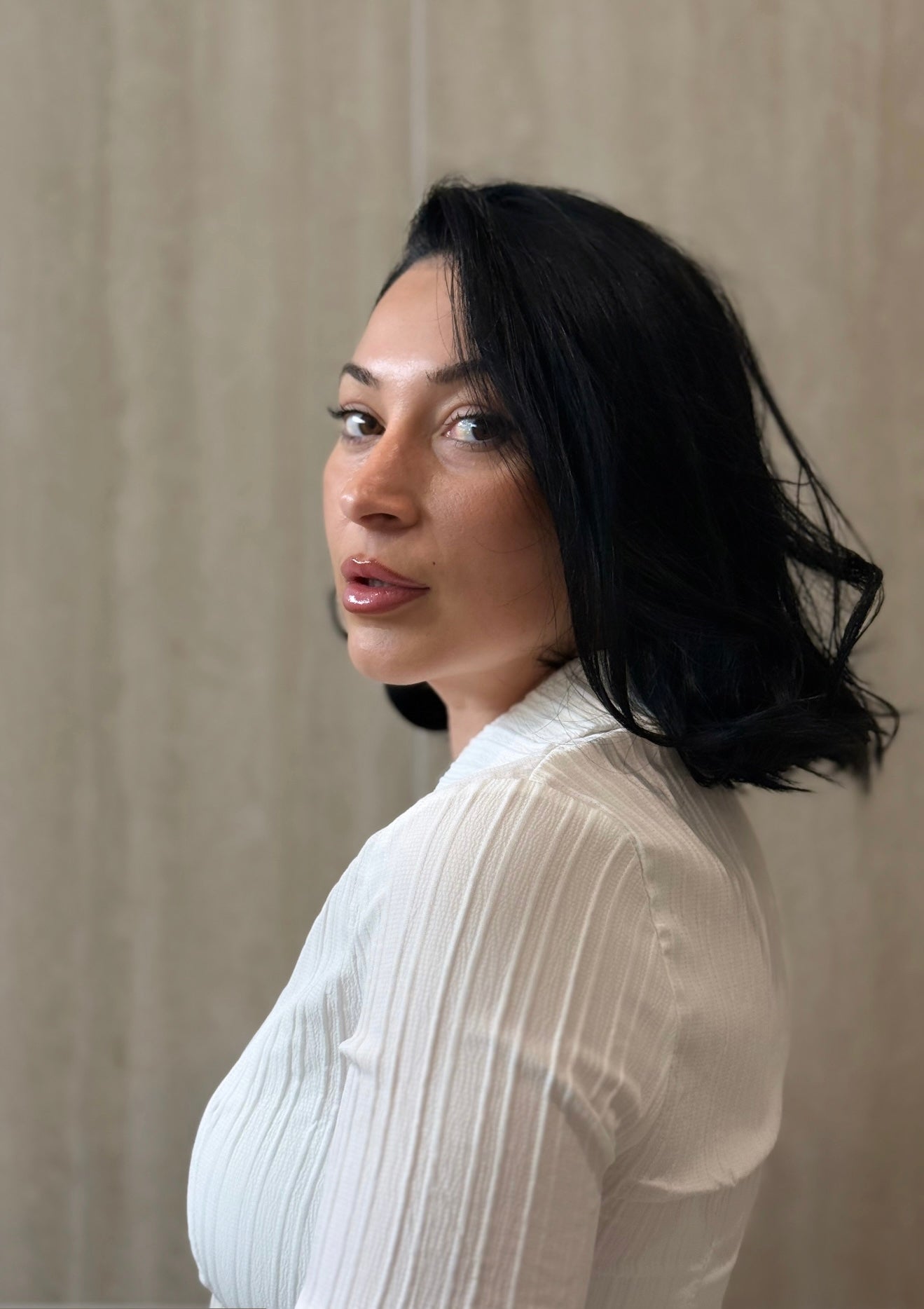 Woman wearing a white blouse against a beige wall